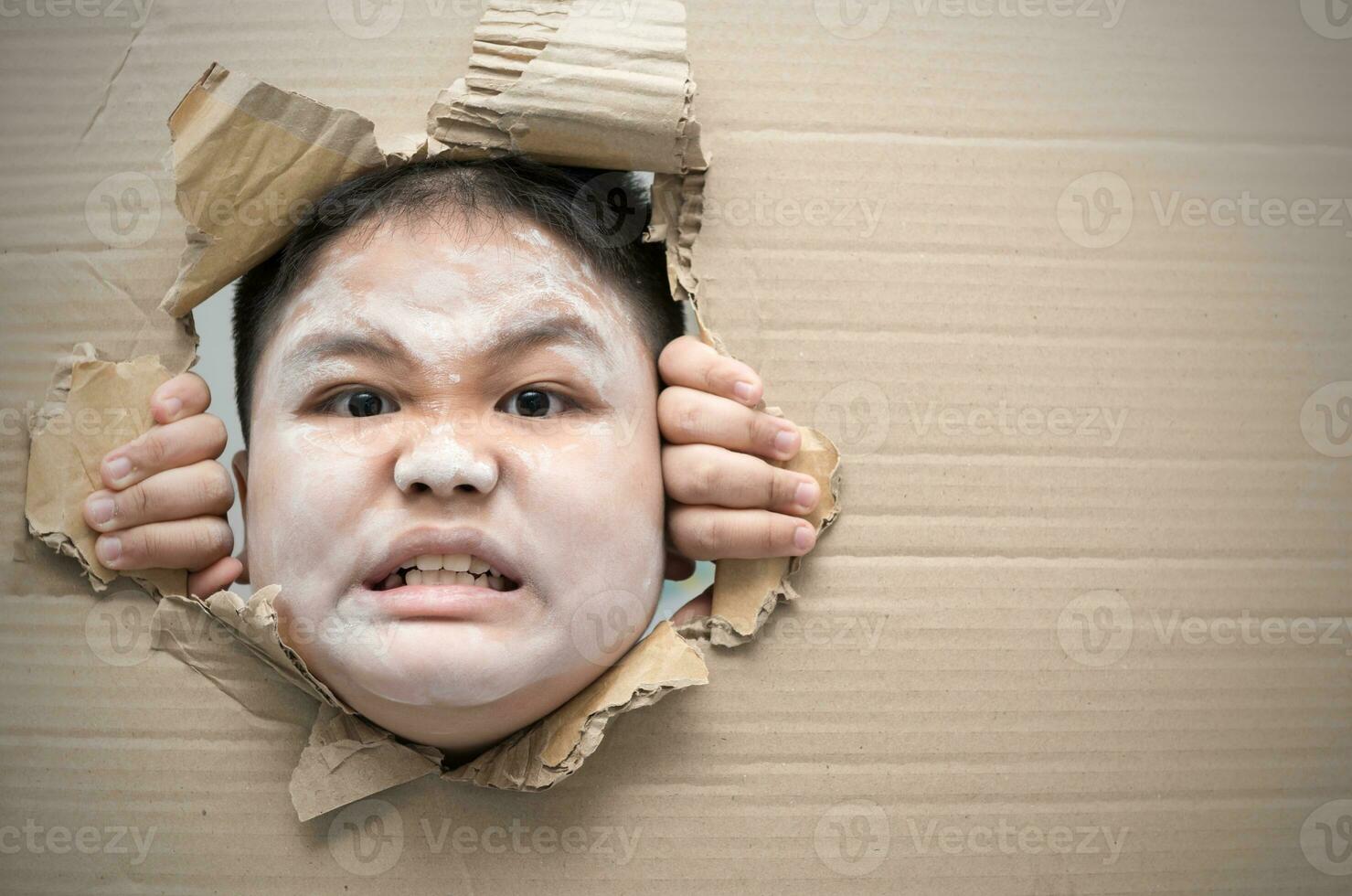 Ghost kid angry and looking through hole on cardboard. photo