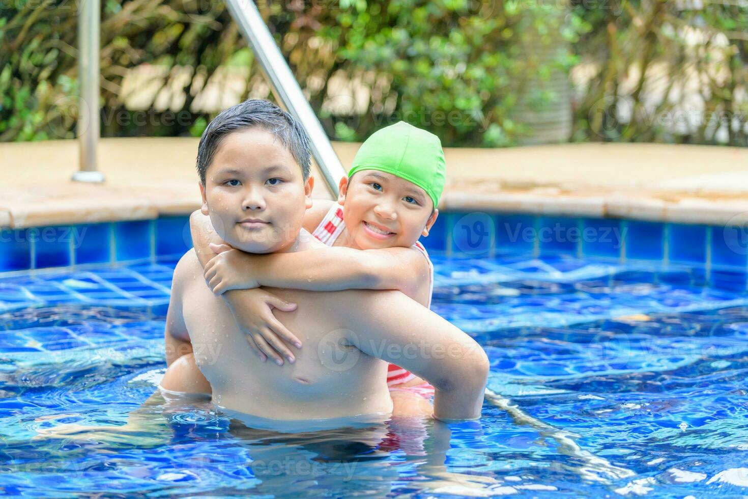 hermano participación hermana en su espalda en nadando piscina foto