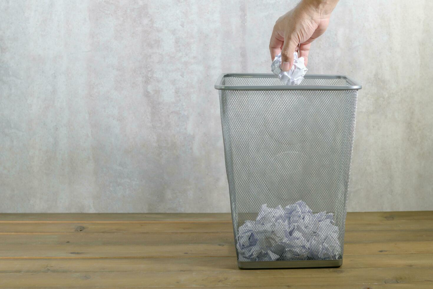 Hand man putting crumpled paper into trash photo