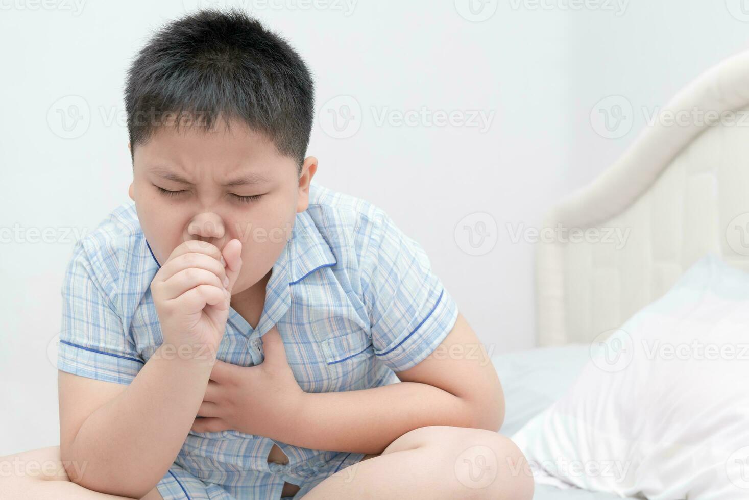 Sick obese boy is coughing and throat infection photo