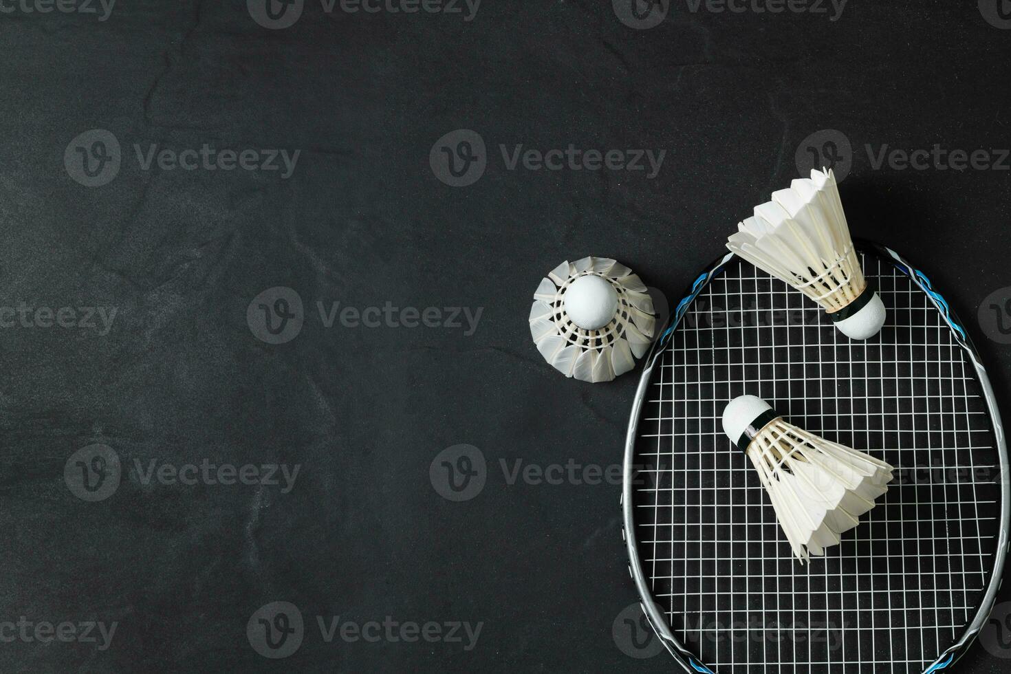 Shuttlecocks and badminton racket on black background photo