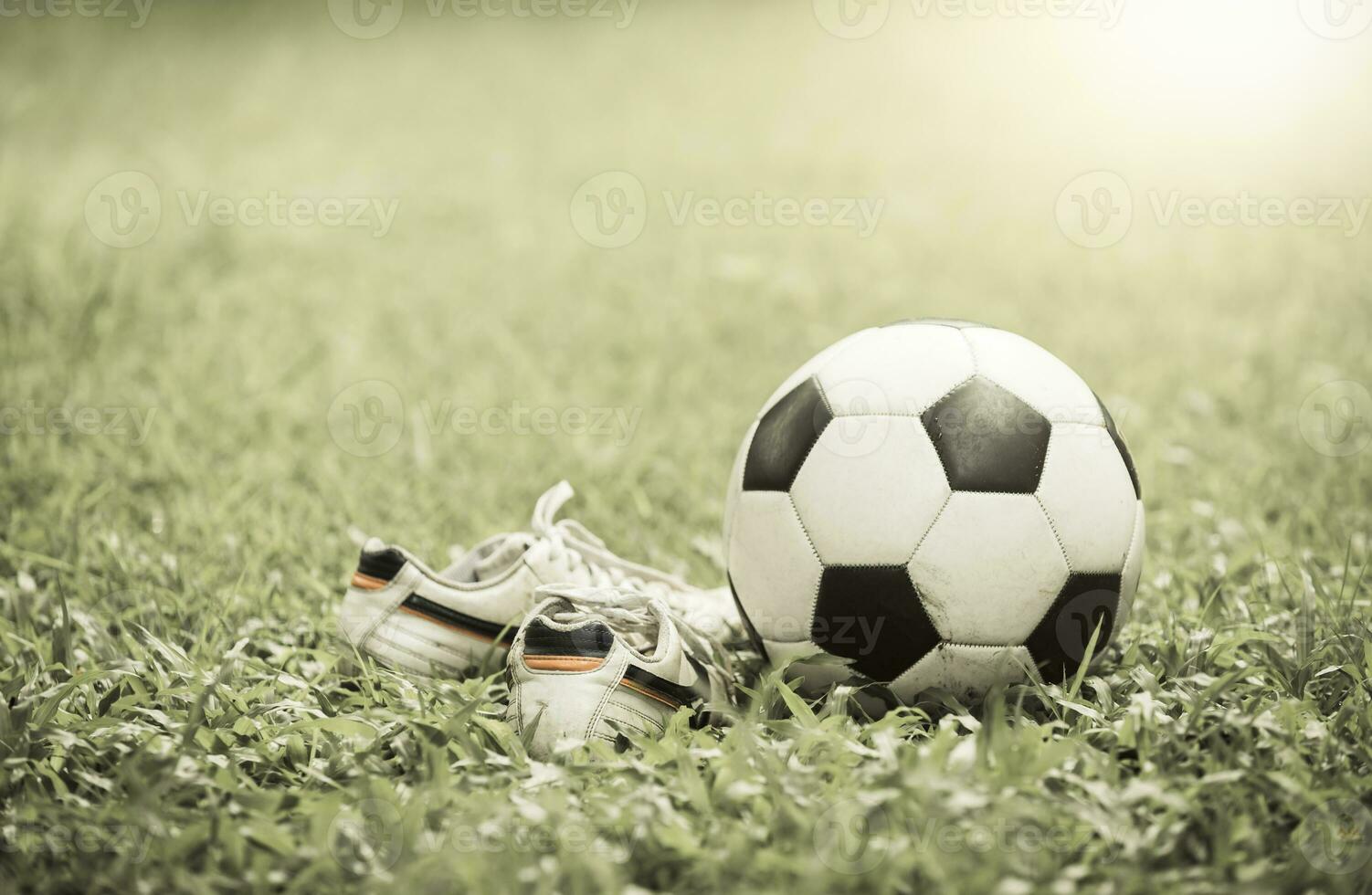 football on grass and stud shoe on vintage tone photo