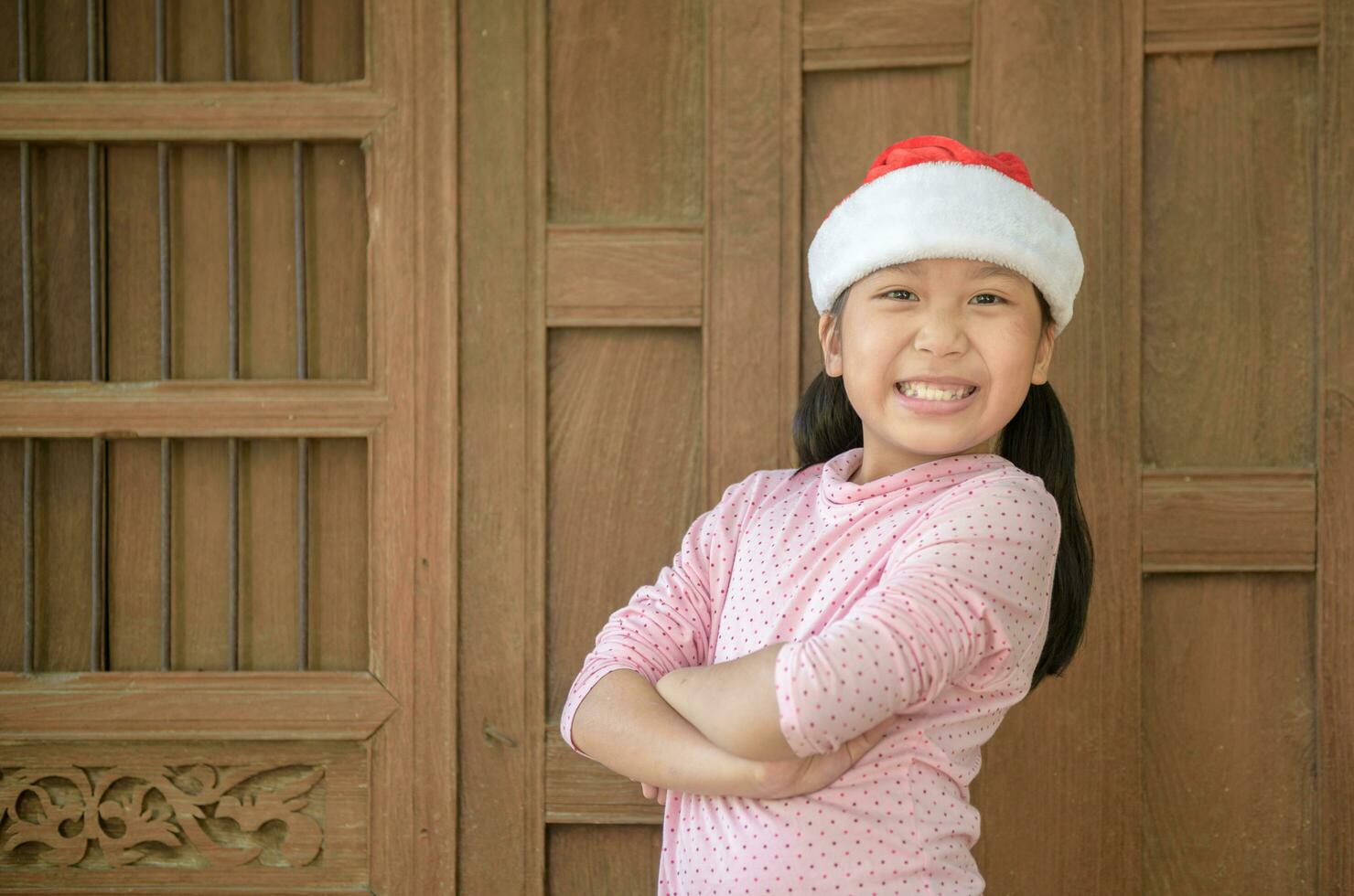 linda asiático niña vistiendo Papa Noel sombrero sonrisa en antiguo madera pared foto