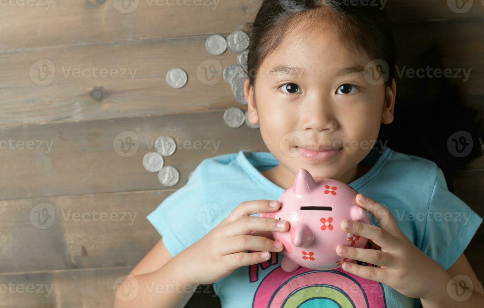 cute girl hold a pig bank on the vintage wood background photo