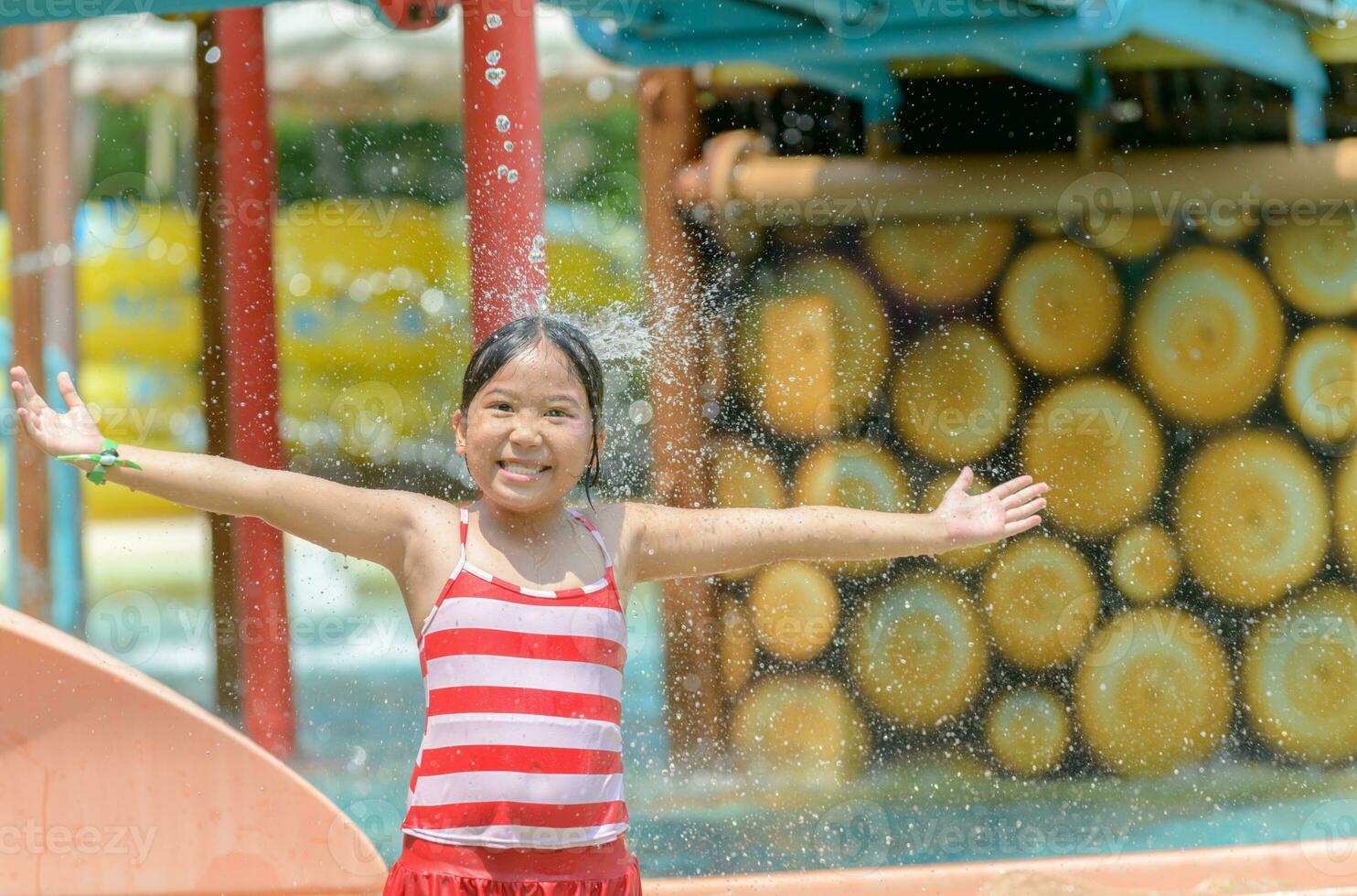 contento pequeño caucásico niña jugando agua a parque acúatico foto