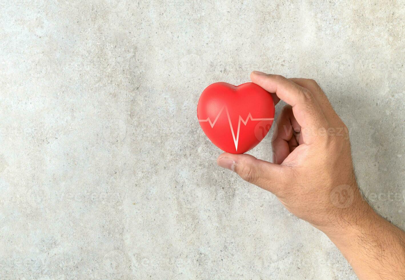 Man holding a red heart shape on marble table photo