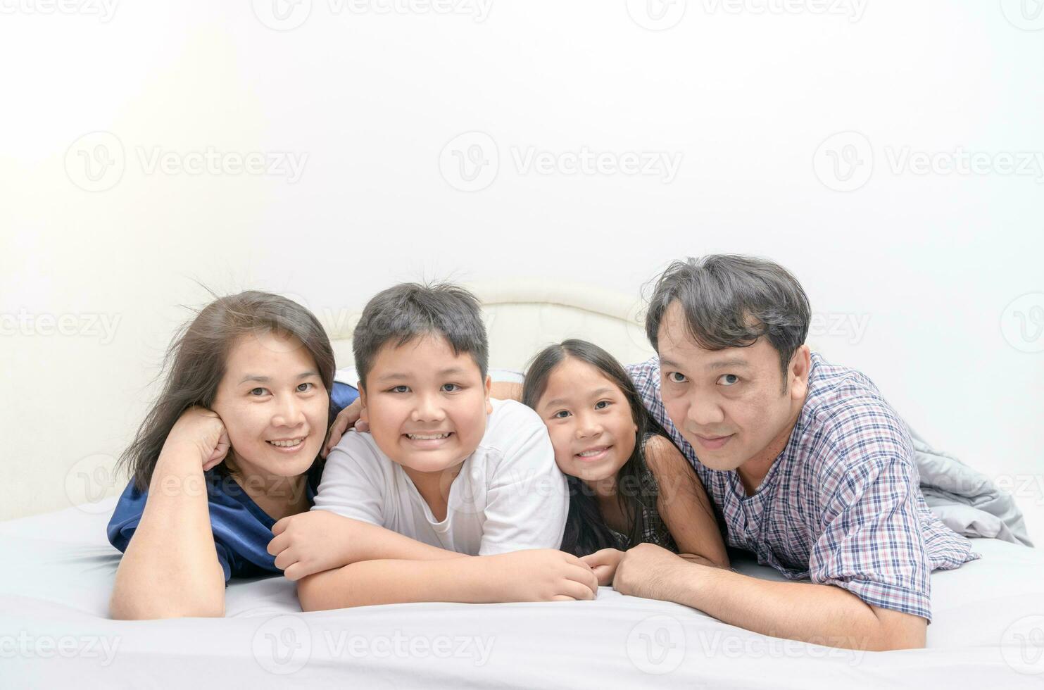 asiático contento joven familia acostado en cama juntos foto