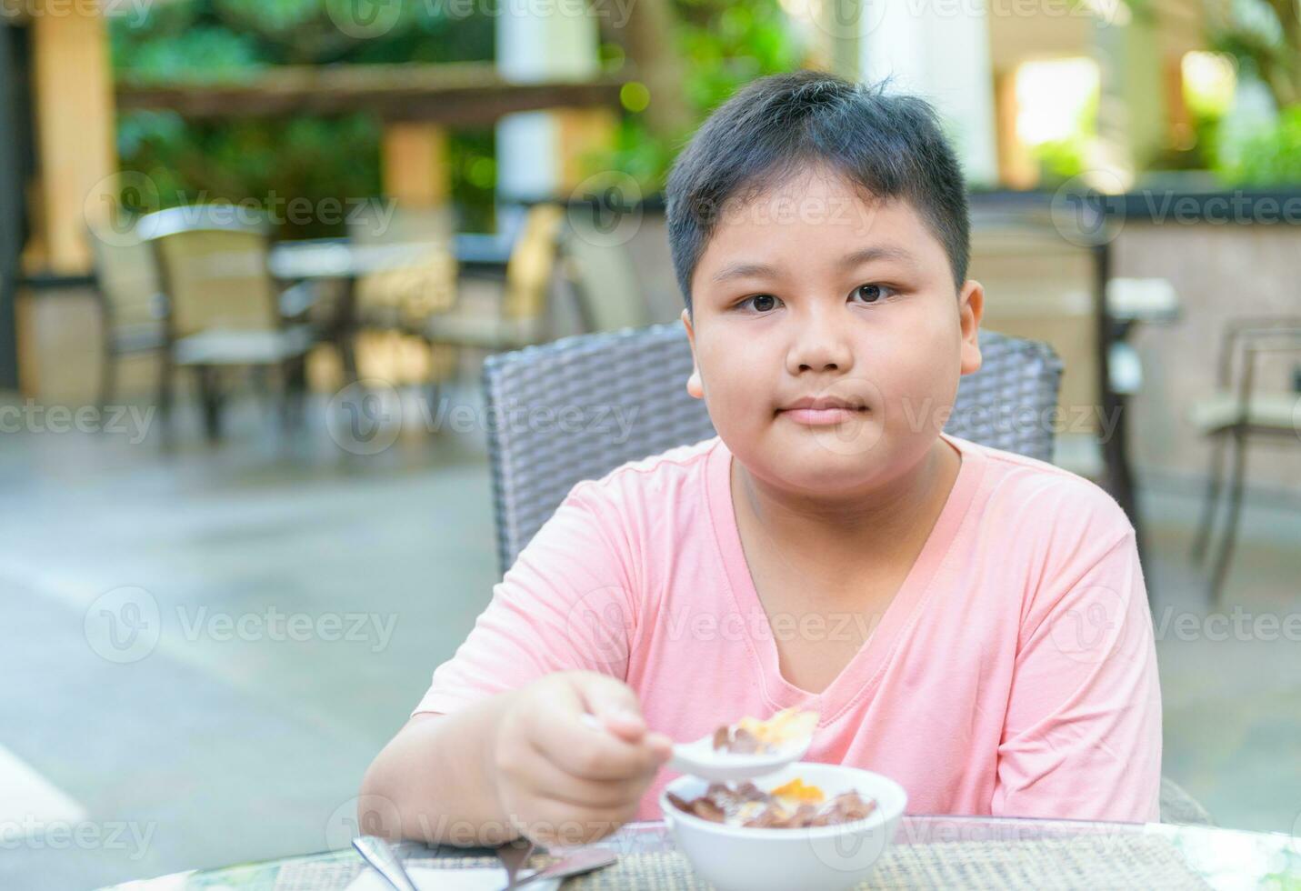 Obese fat boy eating cereal with the milk photo