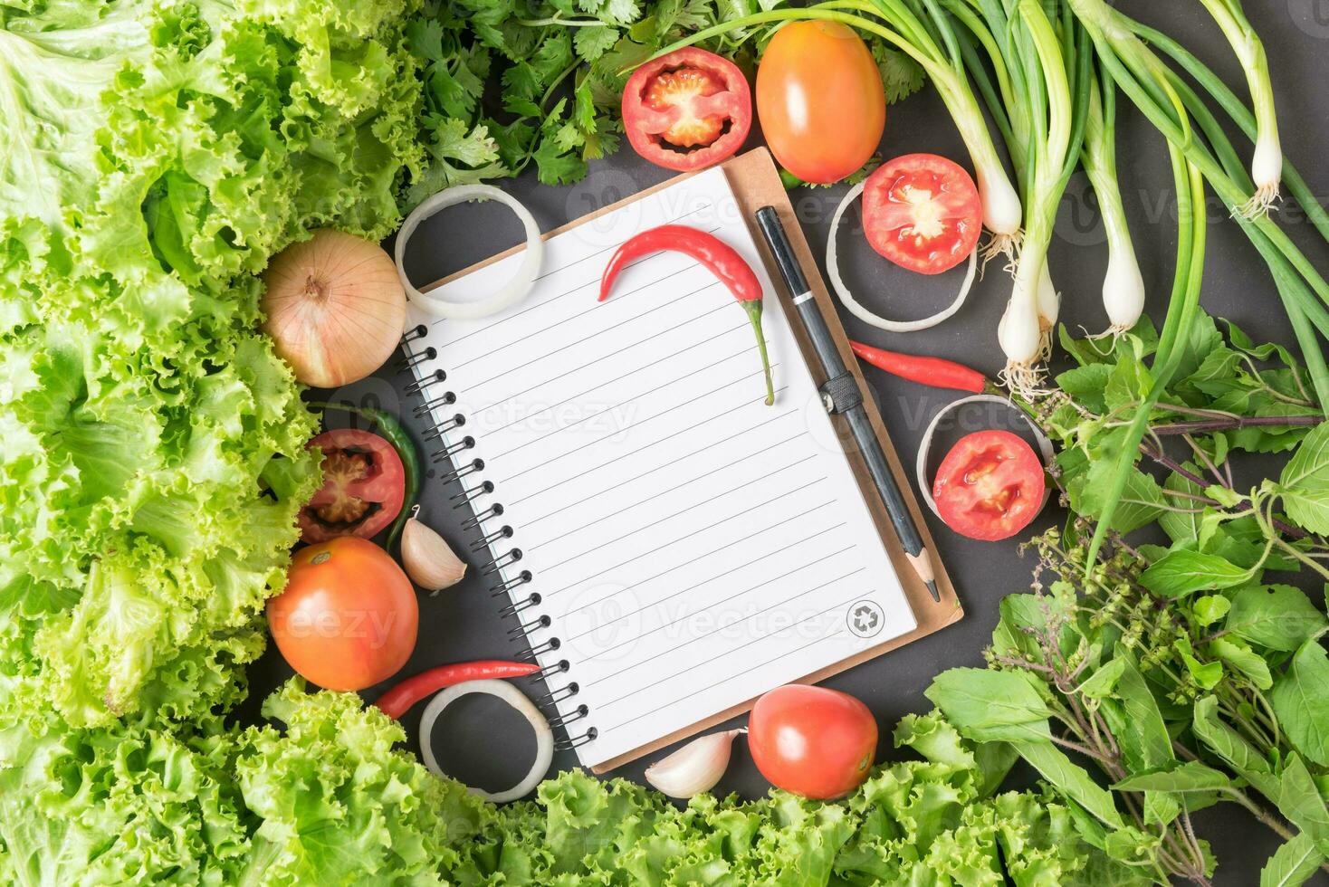 mix vegetables with blank notebook on black bcakground photo