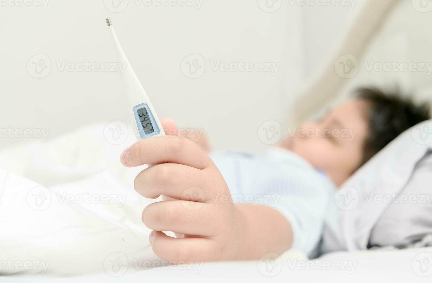 enfermo niño tendido en cama y participación termómetro foto