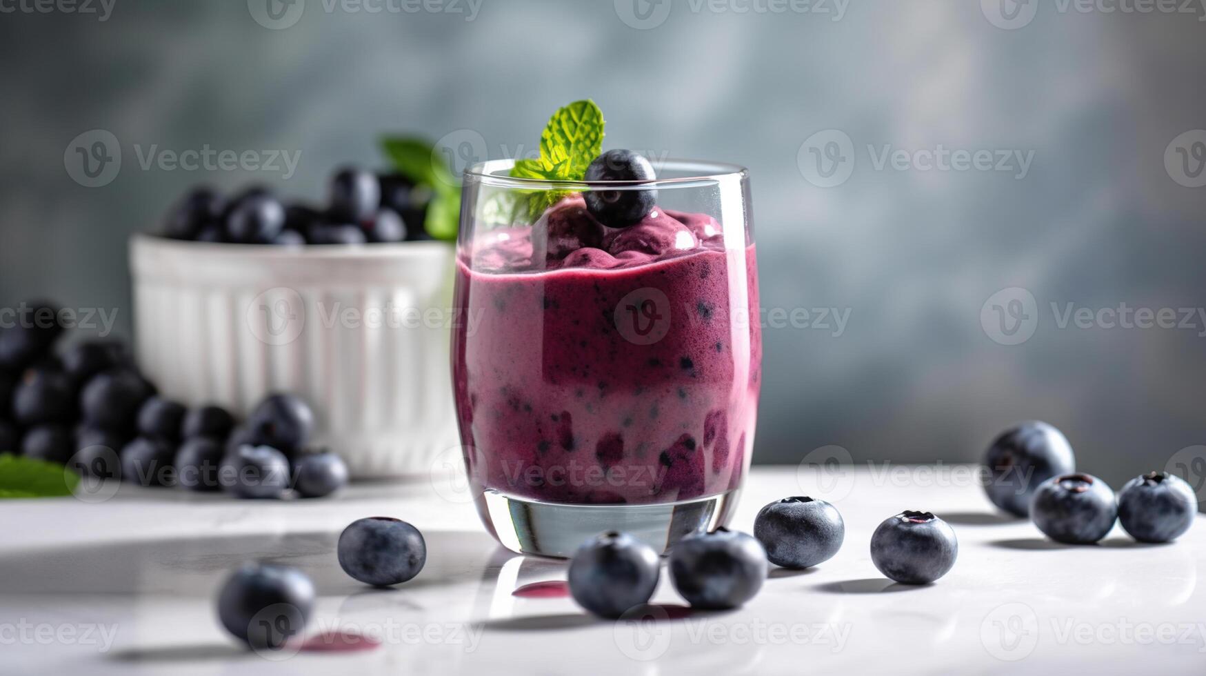 Glass of blueberry smoothie with mint and fresh berries on white marble table. photo
