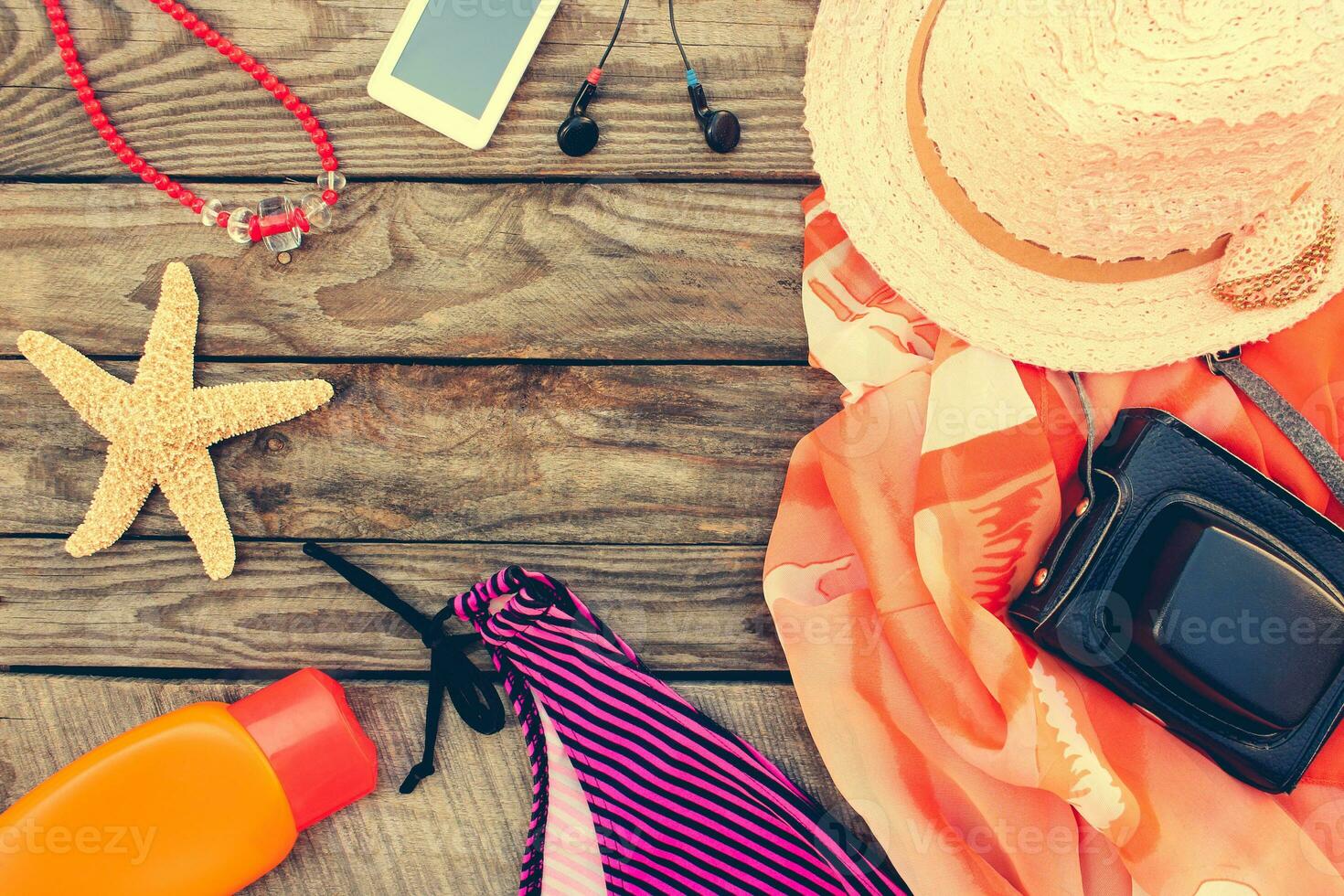 Summer women's beach accessories for your sea holiday on the old wooden background. Toned image. photo