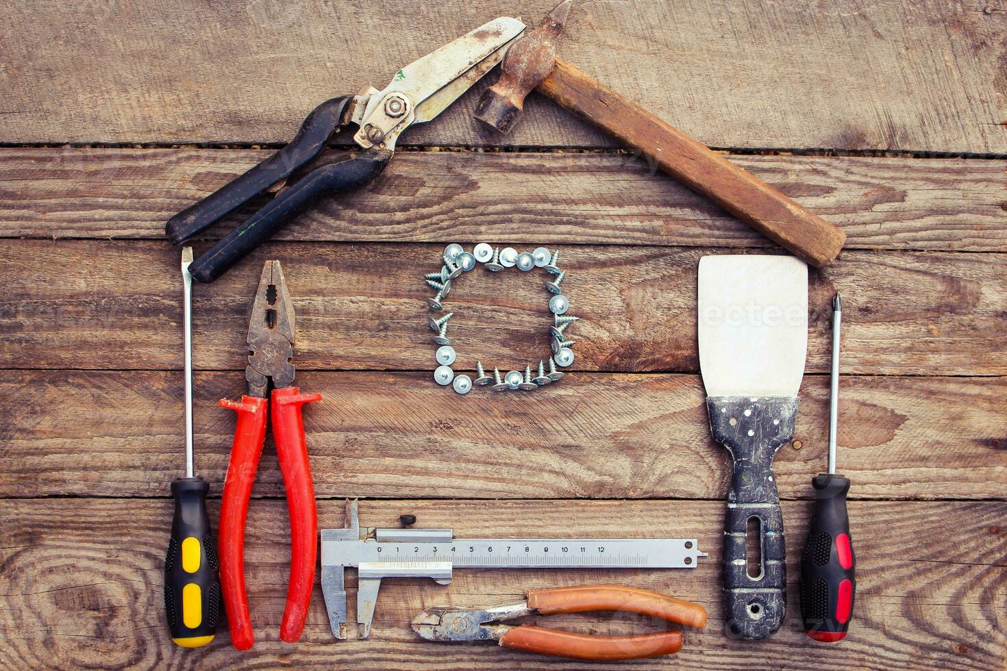 Construction tools in the form of house on wooden background. photo
