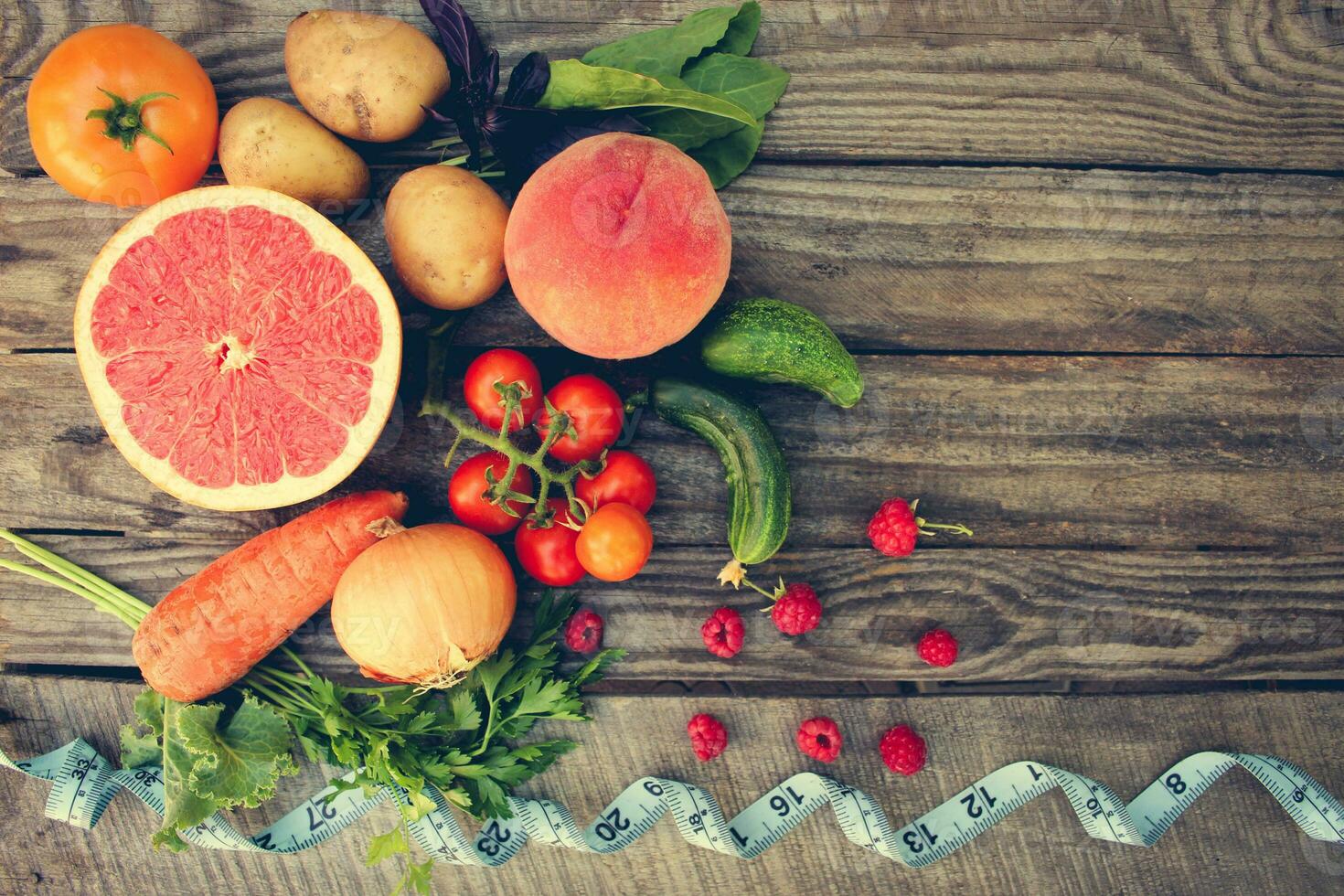Fruits, vegetables and in measure tape in diet on wooden background . Toned image. photo