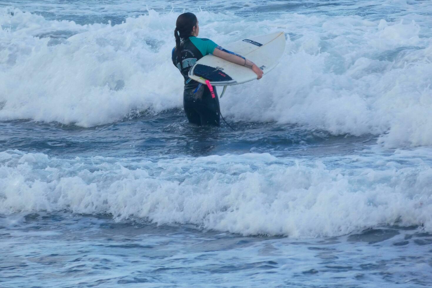 Surfers getting ready to enter the water and walking with the board along the shore. photo