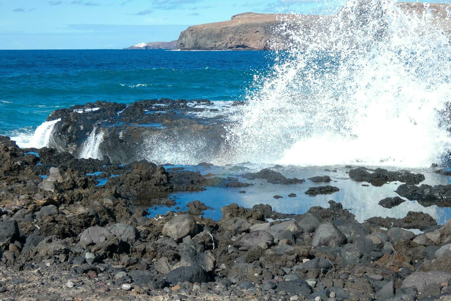 grande olas estrellarse en contra el rocas en el Oceano foto