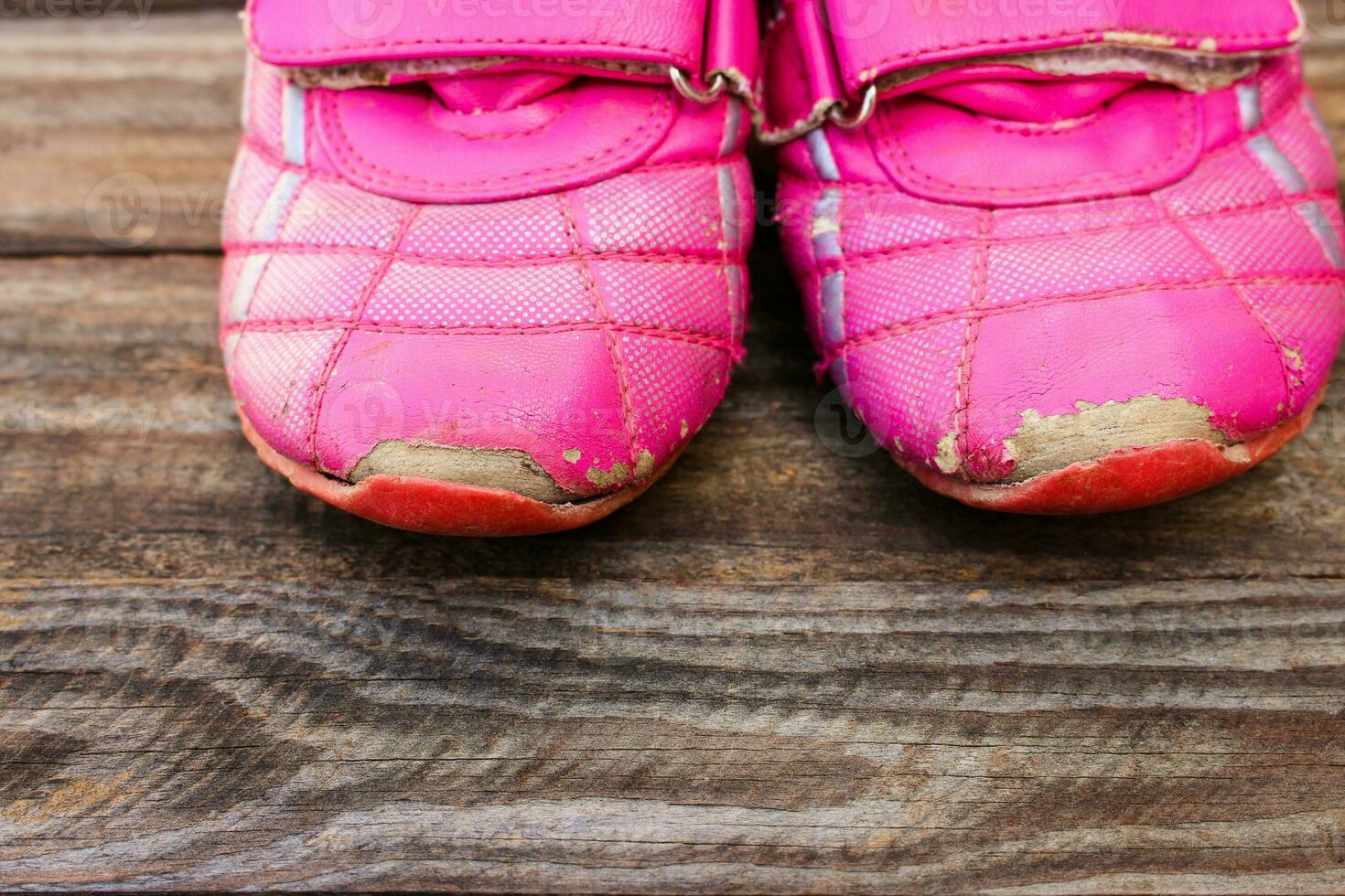 Old child sneakers on wooden background photo