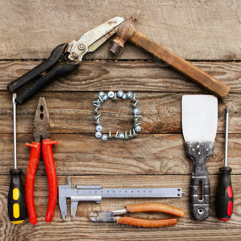 Construction tools in the form of house on wooden background. photo