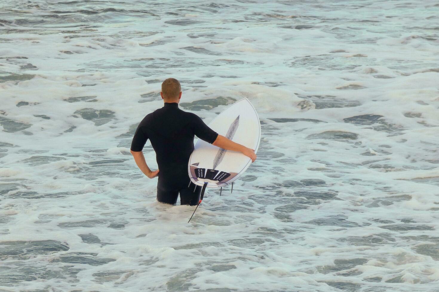 Surfers getting ready to enter the water and walking with the board along the shore. photo