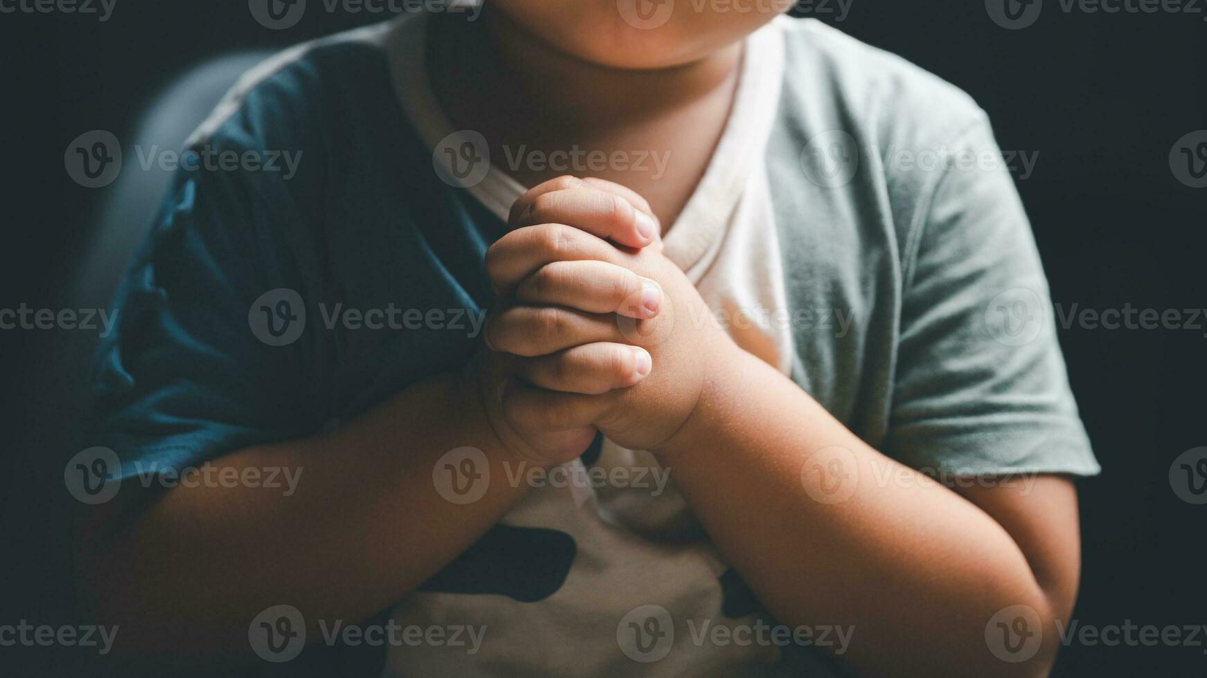 Little boy praying to God with hands held together. Child worship to God. Cute little boy in a Christian family. photo