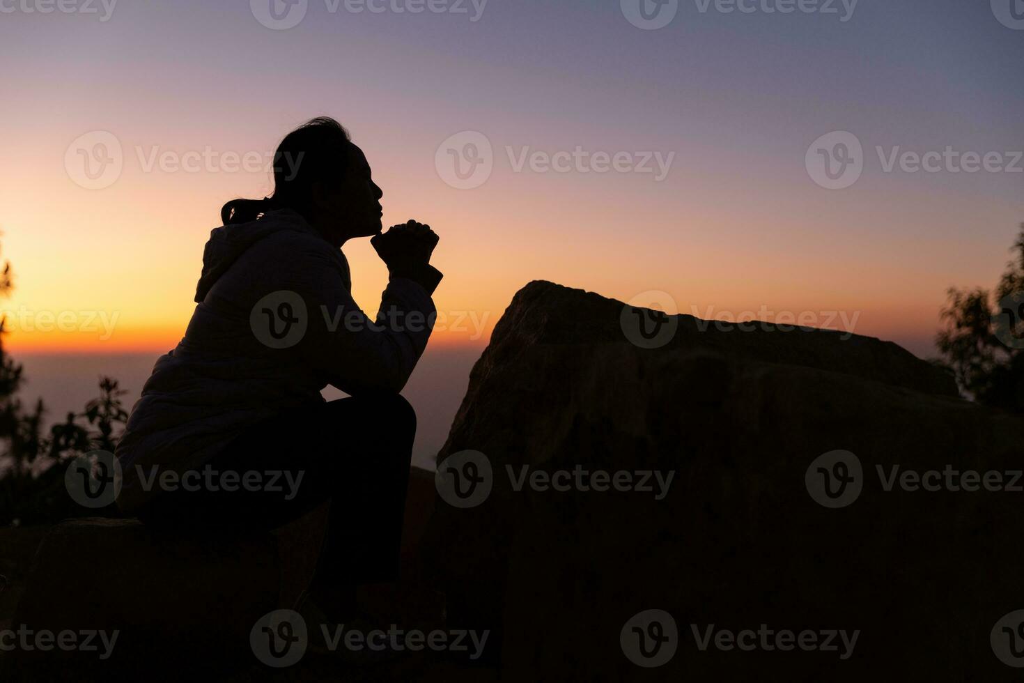 Silhouette with copy space of women hand praying or worship on top of mountain and sunrise sky abstract background. Eucharist therapy god blesses help, hope, and faith, Christian religion concept. photo