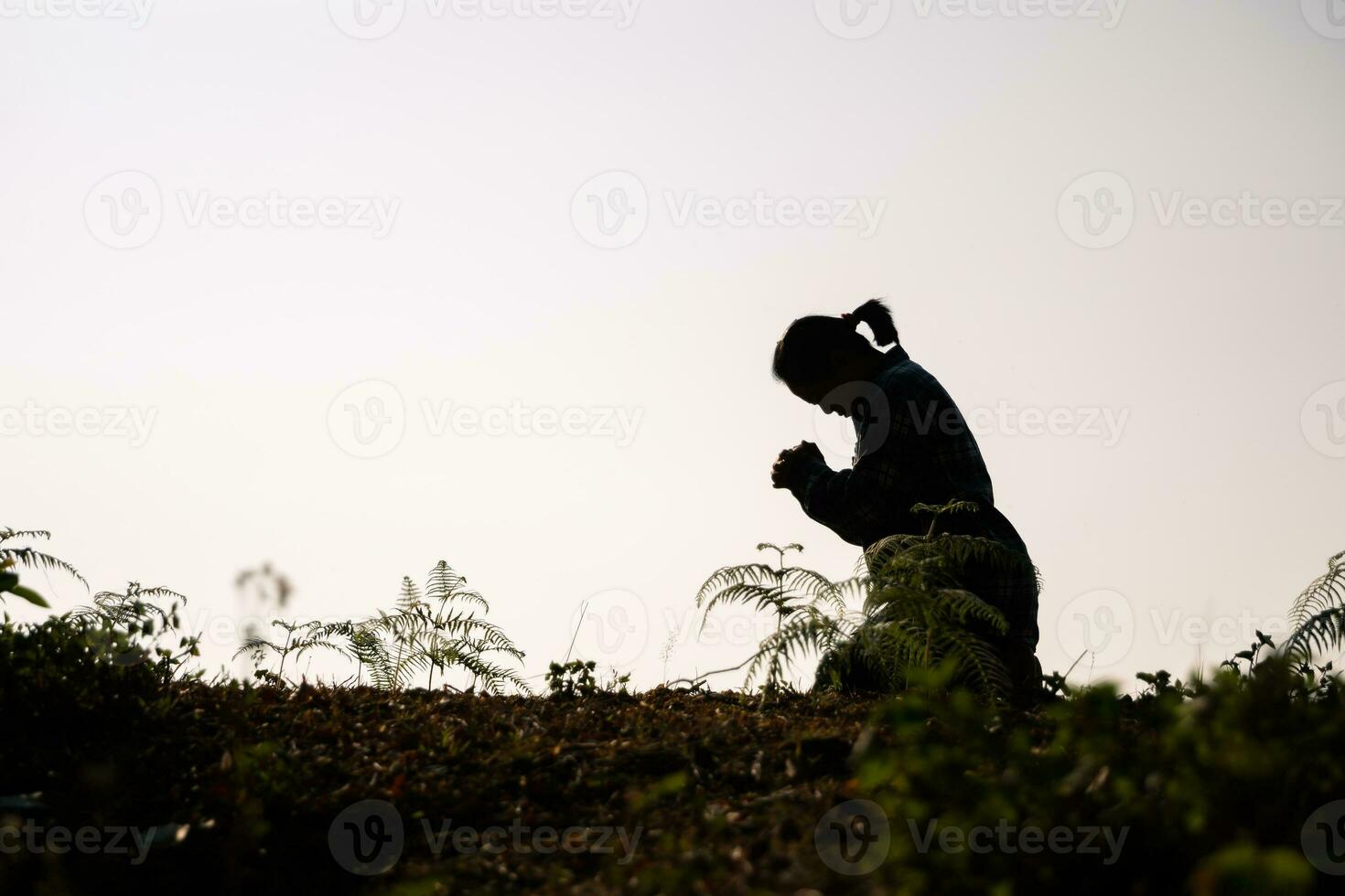 Silhouette of woman kneeling down praying for worship God at white background. Christians pray to jesus christ for calmness. In morning people got to a quiet place and prayed. copy space. photo