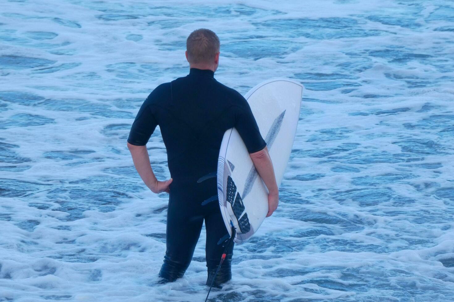 Surfers getting ready to enter the water and walking with the board along the shore. photo