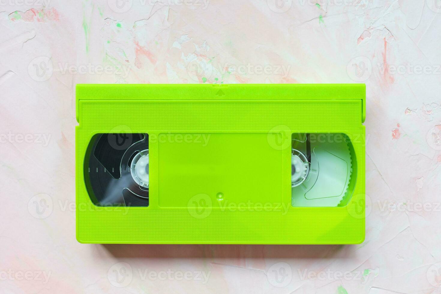 Green vintage VHS video tape on pink background photo