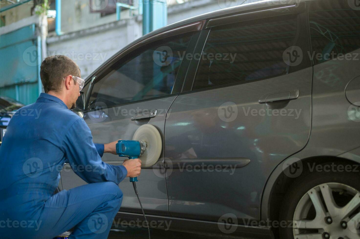 Caucasian man is using car polishing machine in repair mechanic painting shop photo