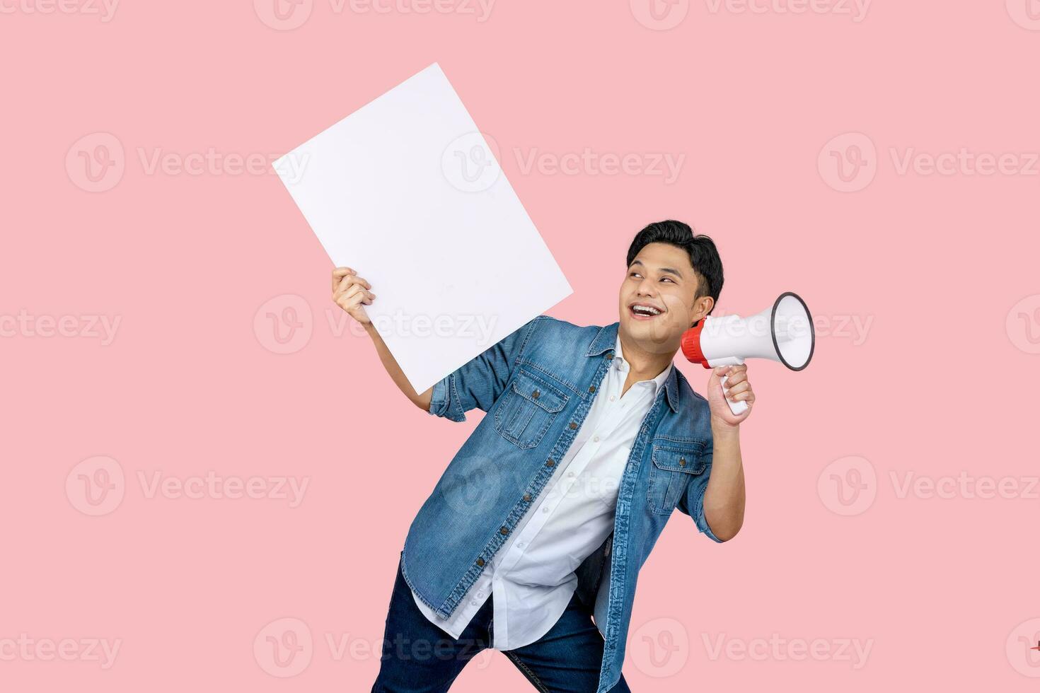 Handsome man holding megaphone and holding blank sign on pink background photo