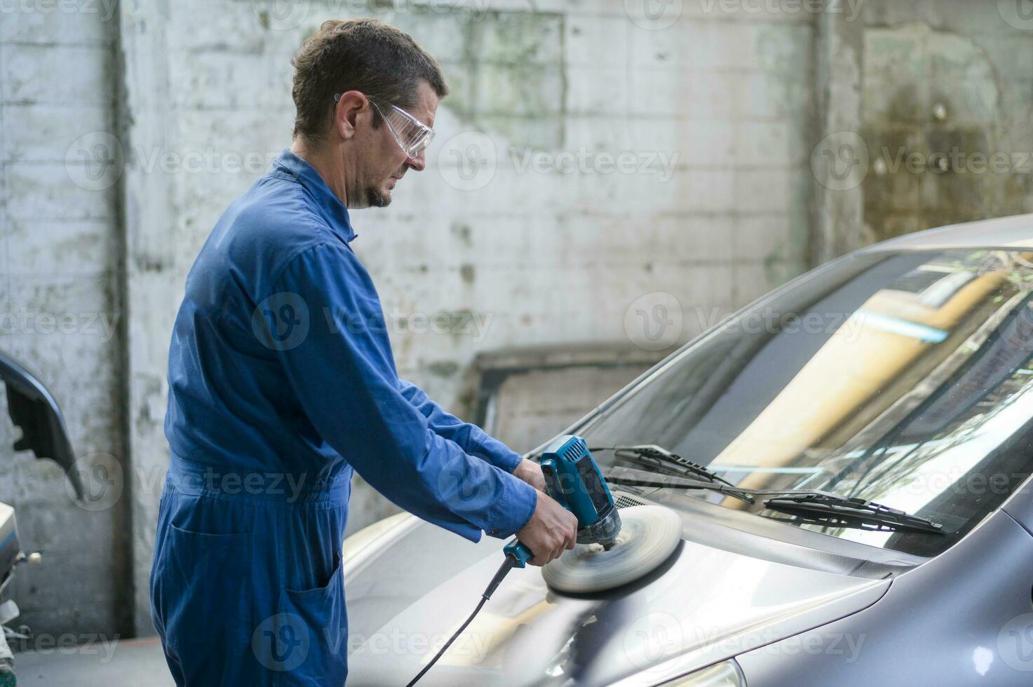 Caucasian man is using car polishing machine in repair mechanic painting shop photo