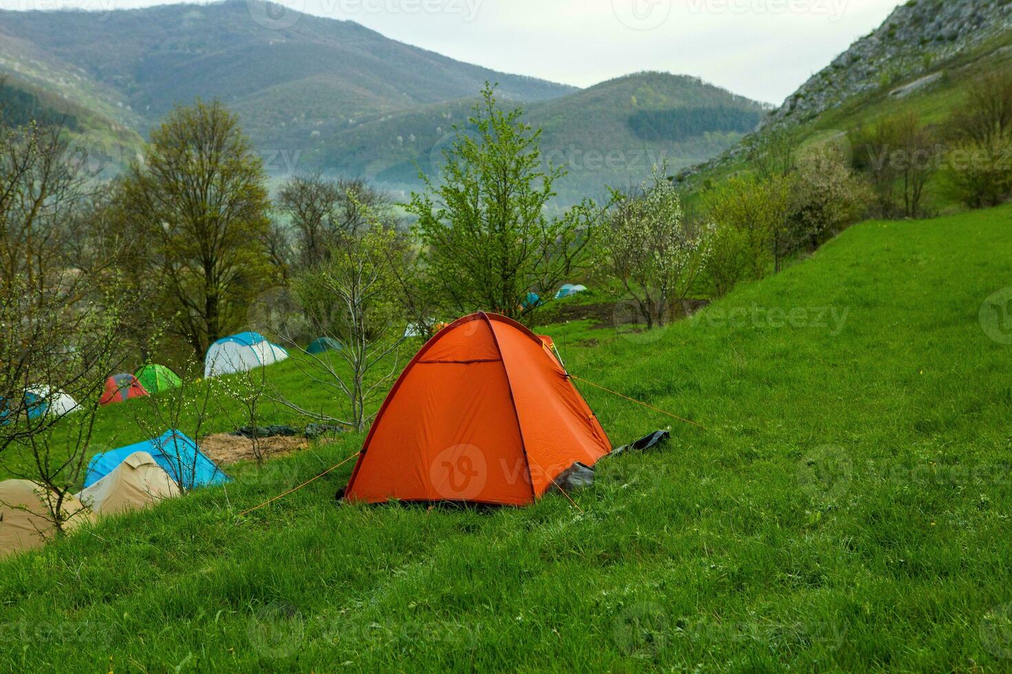 Camping tents on a green meadow in the mountains in spring. Rest with the tent in nature photo
