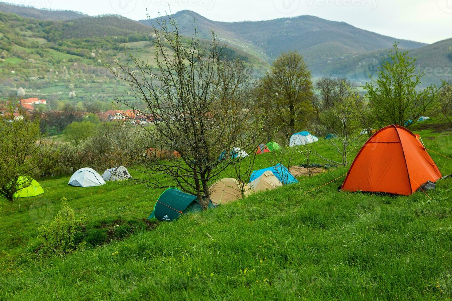 Camping tents on a green meadow in the mountains in spring. Rest with the tent in nature photo