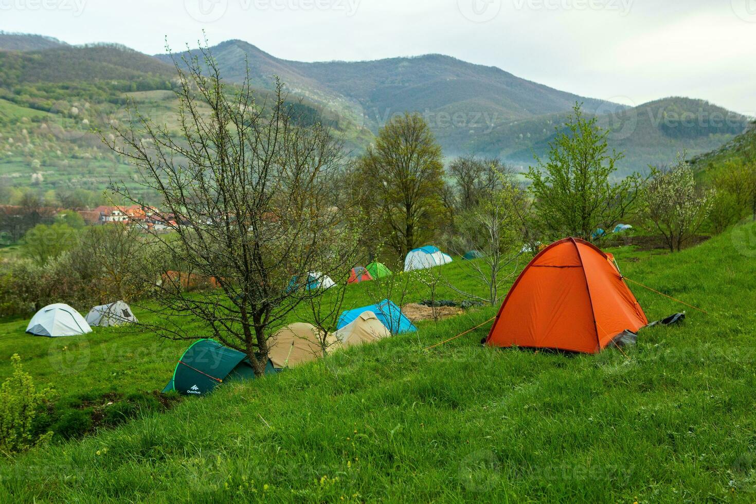 Camping tents on a green meadow in the mountains in spring. Rest with the tent in nature photo