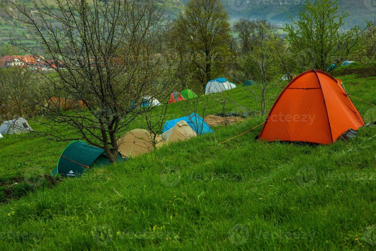 Camping tents on a green meadow in the mountains in spring. Rest with the tent in nature photo