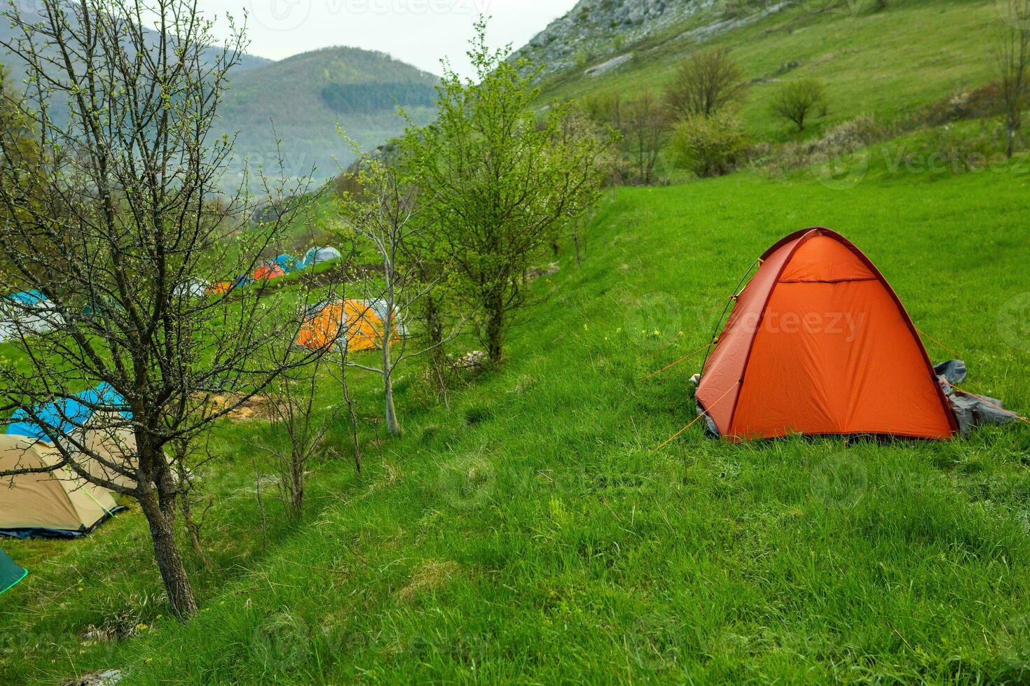Camping tents on a green meadow in the mountains in spring. Rest with the tent in nature photo