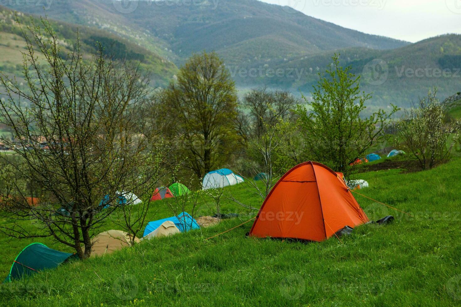 Camping tents on a green meadow in the mountains in spring. Rest with the tent in nature photo