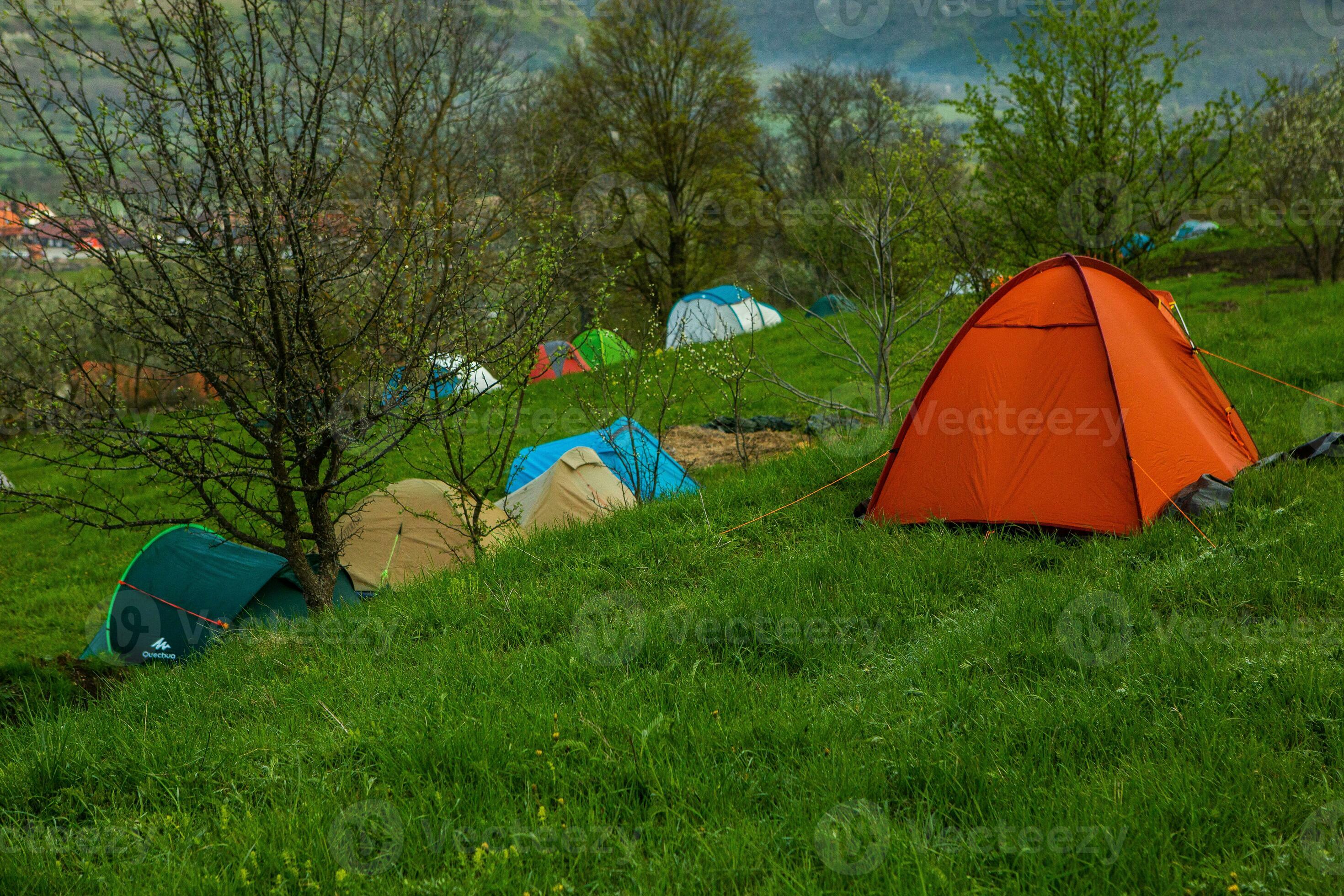Camping tents on a green meadow in the mountains in spring. Rest with