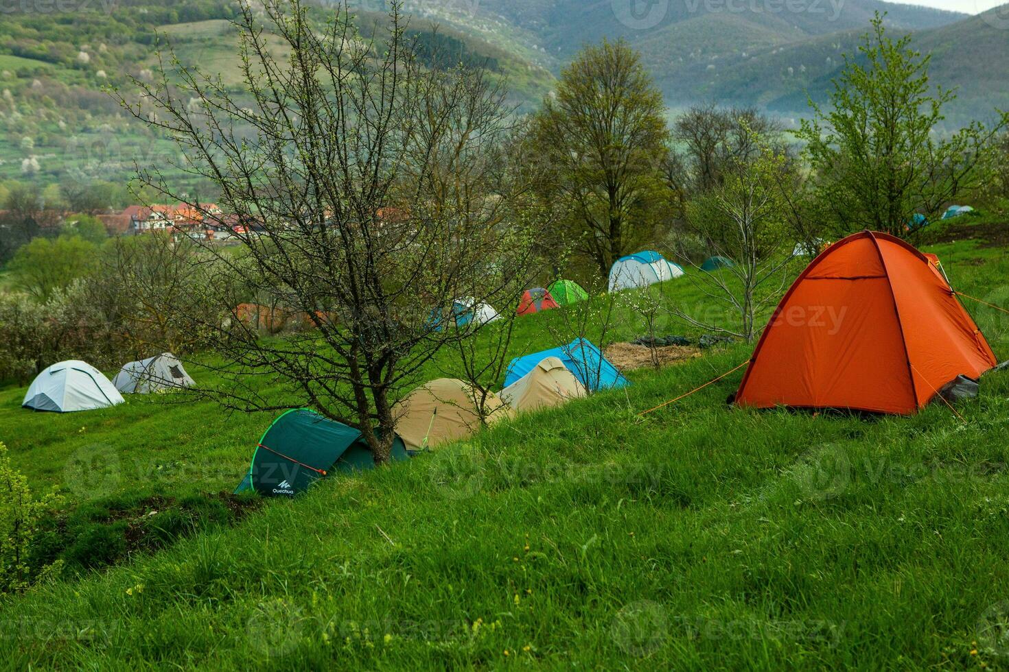 Camping tents on a green meadow in the mountains in spring. Rest with the tent in nature photo