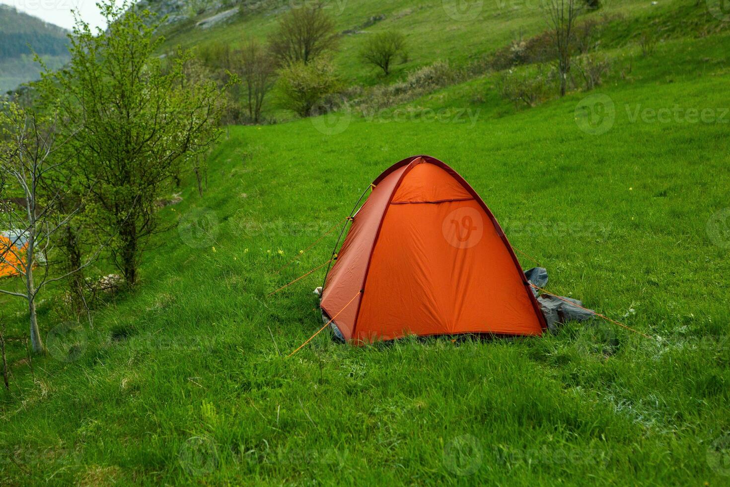 Camping tents on a green meadow in the mountains in spring. Rest with the tent in nature photo