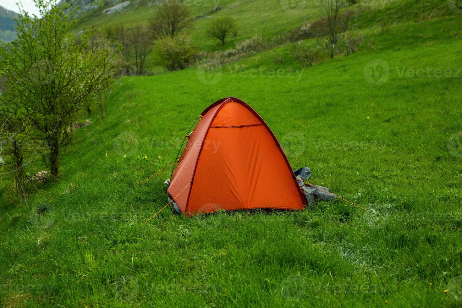 Camping tents on a green meadow in the mountains in spring. Rest with the tent in nature photo