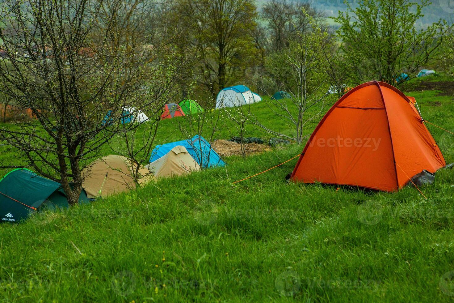 Camping tents on a green meadow in the mountains in spring. Rest with the tent in nature photo
