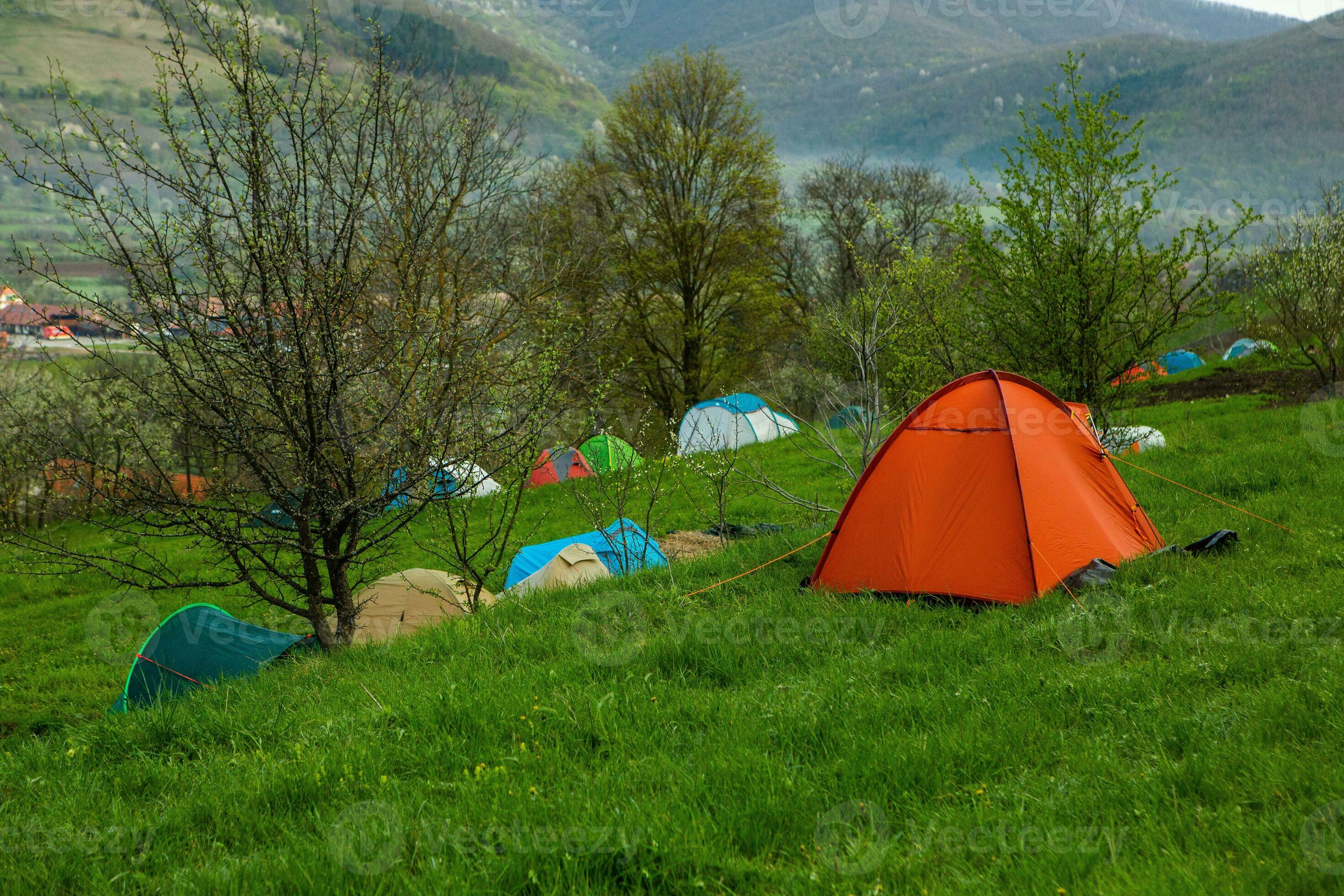 Camping tents on a green meadow in the mountains in spring. Rest with