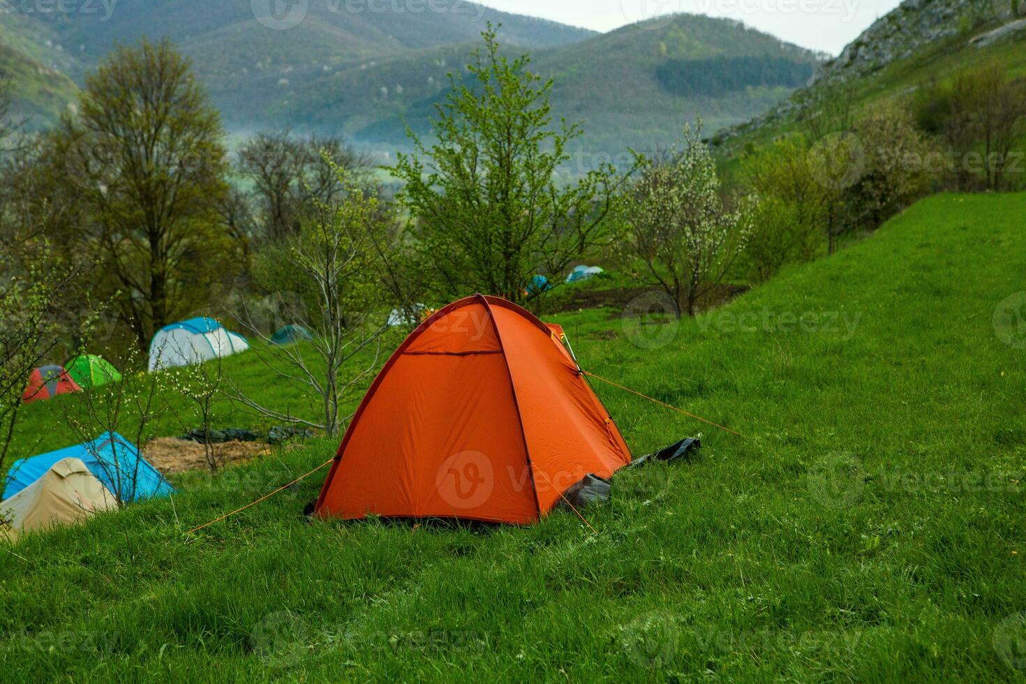 Camping tents on a green meadow in the mountains in spring. Rest with the tent in nature photo