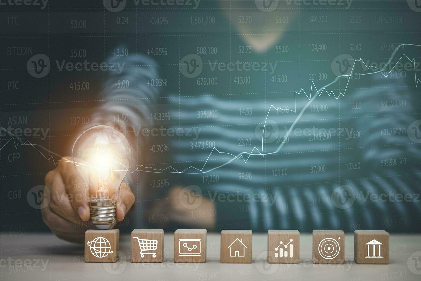 Man hand holding light bulb with Business icon on wood cube and working on desk, Creativity, and innovation are keys to success. Concept of new idea and innovation with Brain and light bulbs. photo
