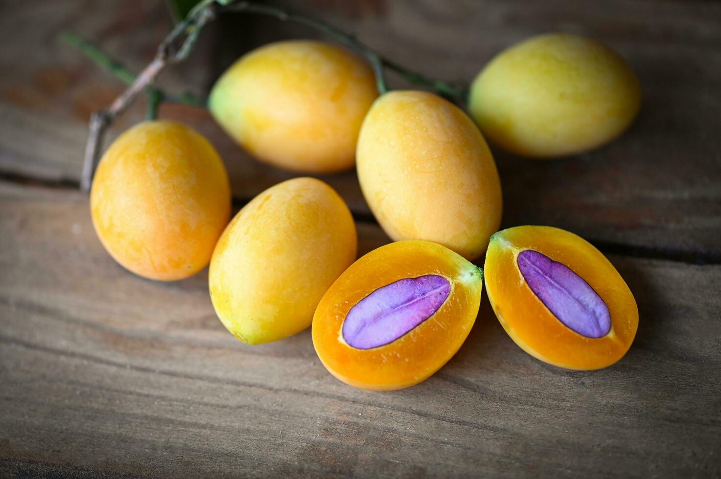 tropical fruit Name in Thailand Sweet Yellow Marian Plum Maprang Plango or Mayong chid, Marian plum fruit and leaves in plate on wooden background photo