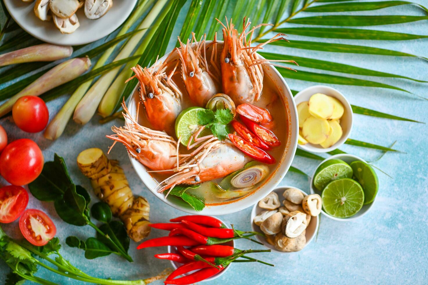 Shrimp soup on seafood soup bowl with thai herb and spices, Thai Food Tom Yum Kung, Hot and sour spicy shrimps prawns soup  curry lemon lime galangal red chili straw mushroom on table food photo