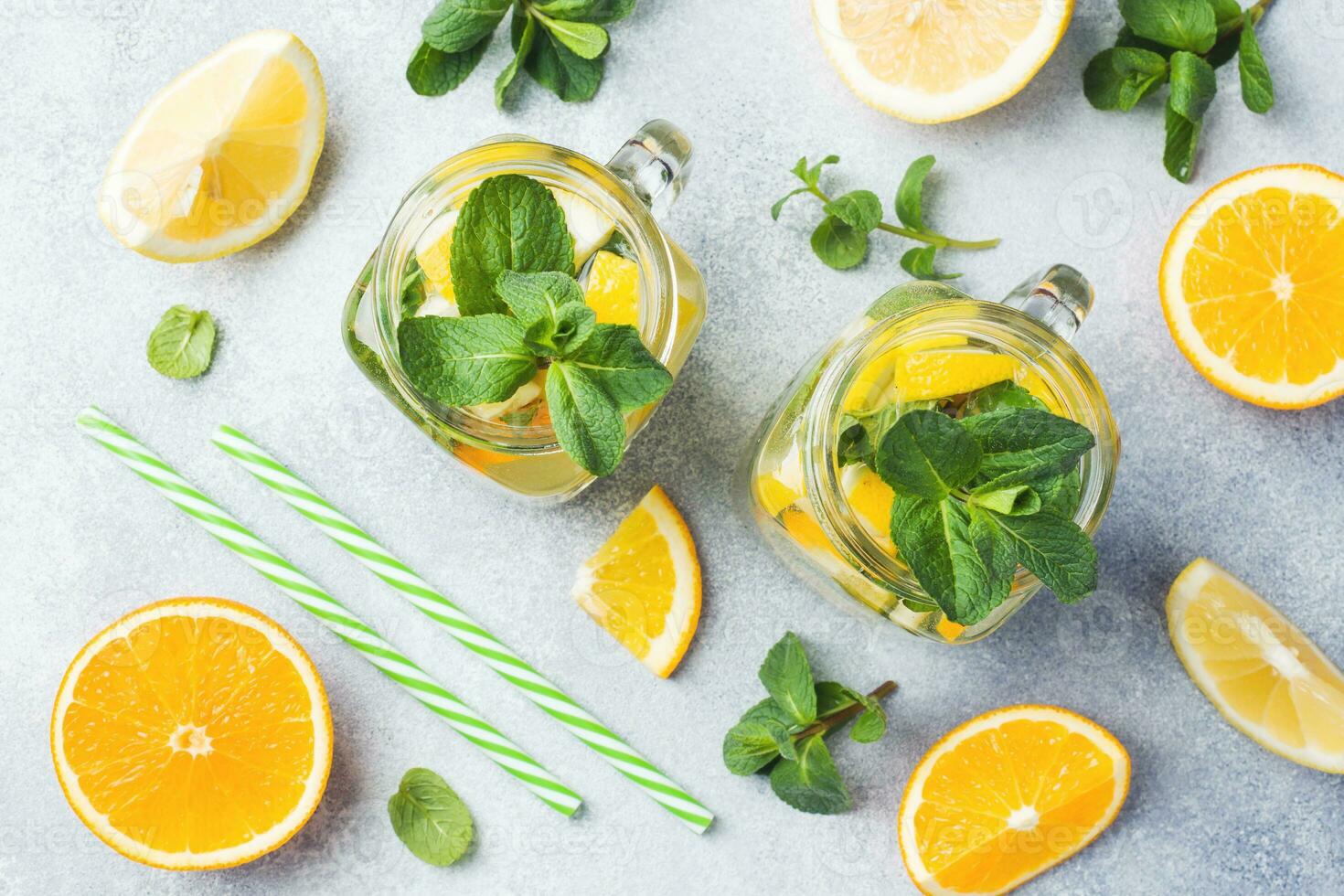 Lemonade drink of soda water, lemon and mint leaves in jar on light background. photo