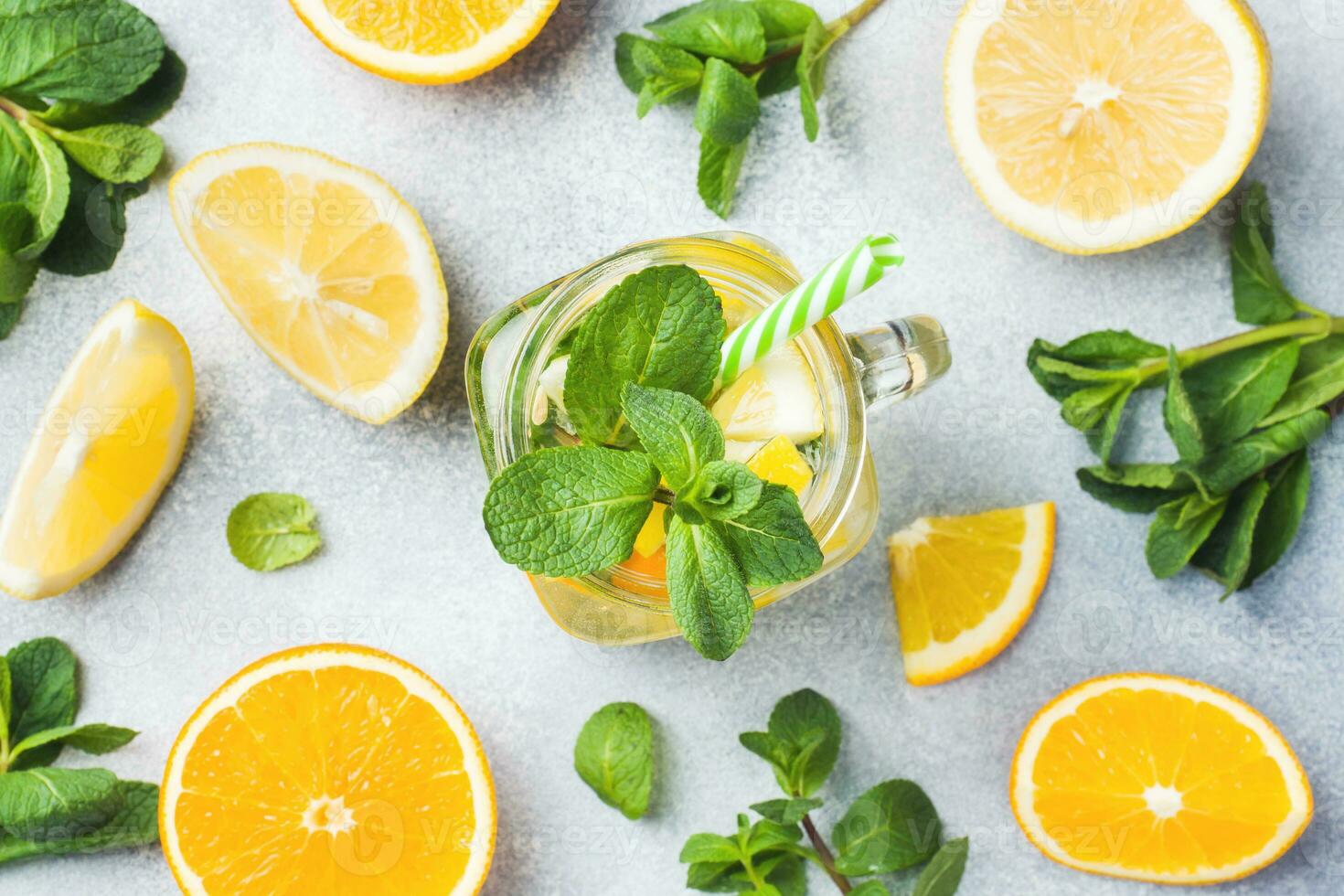 Lemonade drink of soda water, lemon and mint leaves in jar on light background. photo