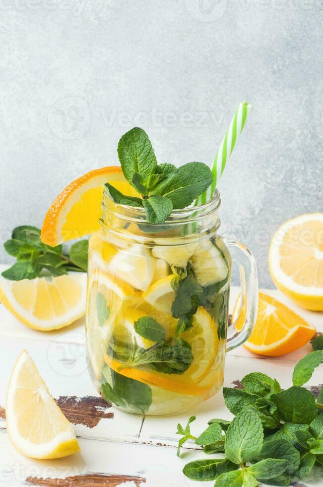 Lemonade drink of soda water, lemon and mint leaves in jar on light background. Copy space photo